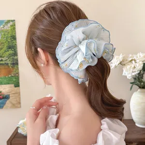 Detail of light blue floral chiffon scrunchie showing layered texture and soft ruffles