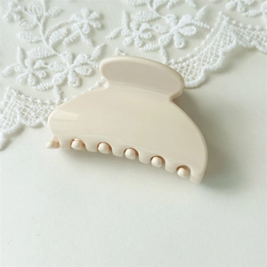 Macro detail of glossy cream-colored fan hair claw clip on elegant lace background