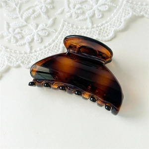 Detailed view of dark tortoiseshell claw clip with acetate finish and lace background