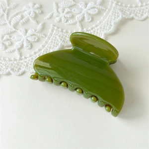 Detail of elegant olive green fan-shaped hair claw clip with glossy finish on lace