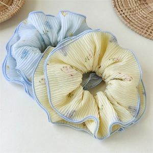 Pastel floral scrunchies in blue and yellow with pleated texture on white background