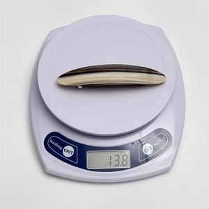 Detail view of acetate hair clip weighing 13.8g on a digital scale for size verification