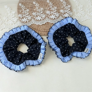 Detail von blauem Karo-Haargummi mit Polka-Dots und handgemachtem Etikett auf Matte