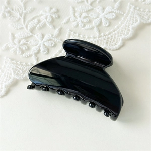 Close-up of a glossy black fan-shaped hair claw clip with elegant lace detailing