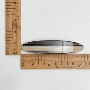 Detail view of 9.5cm striped acetate hair clip with measurements on ruler background