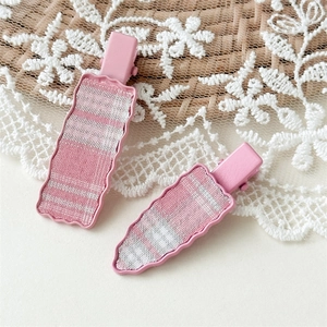 Detail of pink plaid hair clips with wavy edges on lace and wicker background