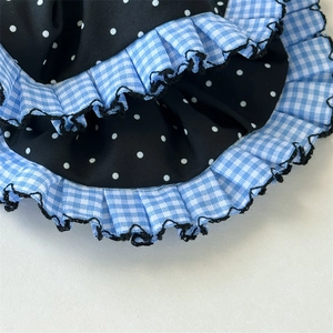 Detail von blauem Gingham und gepunkteten Stofflagen mit schwarzem Wellenrand am Haargummi