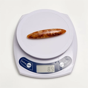 Macro detail of amber acetate hair clip showing weight of 8.9g on digital scale