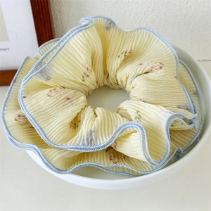 Detail of yellow pleated scrunchie with blue wavy edges and delicate floral patterns