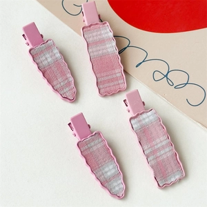 Detail of four pink plaid checkered hair clips with wavy rectangle and carrot shapes