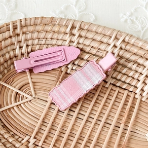 Detail view of pink plaid fabric hair clips showing the wavy edge and metal alligator grip