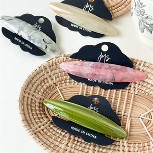 Elegant acetate hair clips in marble and pastel colors on a woven basket display