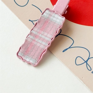 Close-up of pink checkered fabric hair clip with wavy edges and metal duckbill base