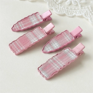 Close-up of pink checkered fabric hair clips with wavy metal base on lace background