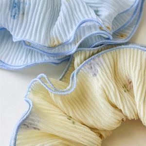 Detailed macro view of light blue and yellow chiffon scrunchies with soft floral patterns