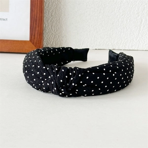 Detail eines schwarz-weiß gepunkteten geknoteten Stirnbands mit Crinkle-Stofftextur