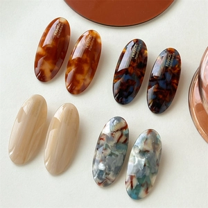 Oval acetate hair clips in amber, tortoiseshell, and marble patterns for women