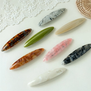 Close-up of acetic acid hair clips in marble and tortoiseshell patterns with handmade logos