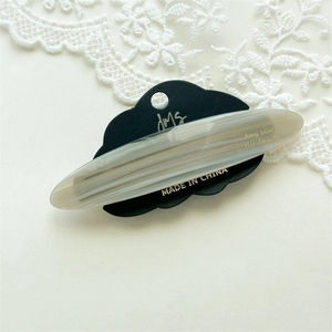 Detailed close-up of marble acetate hair clip with Amy Bear logo on a display card