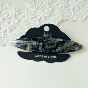 Detail of a handmade marble acetate hair clip on a premium black cloud display card