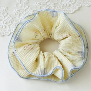 Detail of yellow floral scrunchie with pleated texture and blue stitched edges