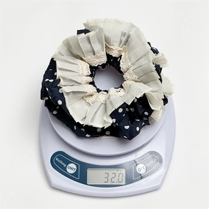 Detailansicht eines Polka-Dot-Spitzen-Scrunchies mit 32,0 Gramm auf einer Digitalwaage