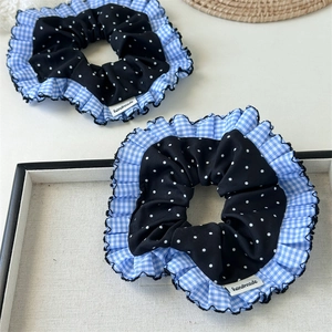 Nahaufnahme von blauem Gingham und schwarzem Polka-Dot-Haargummi mit Handmade-Label