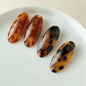 Detailed close-up of four tortoiseshell acetate oval hair clips with France Handmade text
