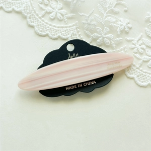 Close-up of pink and white striped acetate hair clip with gold handmade lettering detail