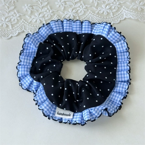 Detail eines blau karierten Haargummis mit Polka-Dots und handgemachtem Etikett