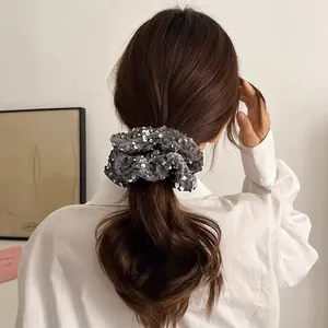 Detail showing a grey sequin scrunchie used for a stylish low ponytail hairstyle