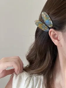 Detail of elegant marble pattern acetate oval hair clips worn by a model as side clips