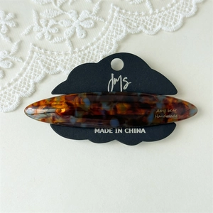 Detailed macro view of tortoiseshell acetate hair clip on brand cloud display card