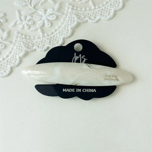 Macro detail of elegant ivory marble acetate hair clip on branded display card