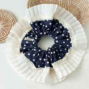 Details von marineblauem Polka-Dot-Stoff und weißer Falten-Chiffon-Spitze am Haargummi