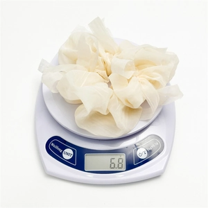 Lightweight cream puff gauze scrunchie weighing 6.8g shown on a white digital scale
