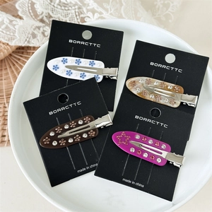 Elegant acetate flower hair clip set with marble texture, rhinestones and pearls on a plate