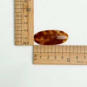 Detailed size view of a 5.5cm tortoiseshell acetate oval hair clip with gold logo