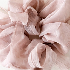 Close-up of light pink puff yarn scrunchie showing soft pleated texture and fabric