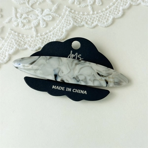 Detail of elegant black and white marble acetate hair clip on presentation card with lace