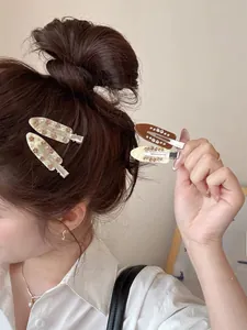 Close-up of four acetate duckbill hair clips with floral patterns and rhinestones