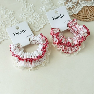 Close-up of red polka dot and plaid scrunchies with white lace edges on display card