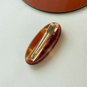 Oval acetate tortoise shell hair clip with a premium golden metal duckbill clamp design