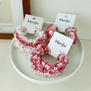 Detailed view of red and white polka dot hair ties with delicate lace edges in a ceramic dish