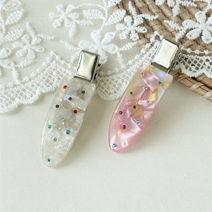 Detailed macro view of pearlescent acrylic hair clips with colorful inlaid rhinestones