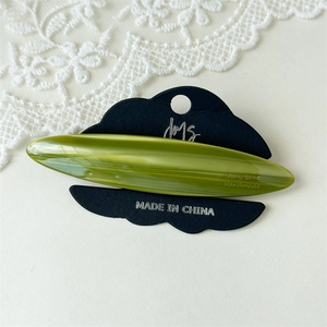 Detailed macro view of olive green marble pattern acetate hair clip on display card