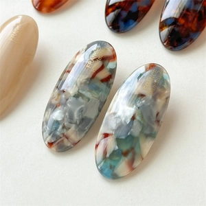Macro shot of oval acetate hair clip with marble texture and gold France Handmade logo