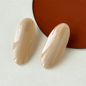 Detailed close-up of beige marble acetate oval hair clips with France Handmade text