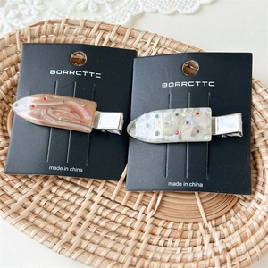 Exquisite marble-textured duckbill hair clips with colorful rhinestones on a display card