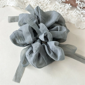 Close-up of elegant grey-blue puff gauze scrunchie with long ribbon and texture details